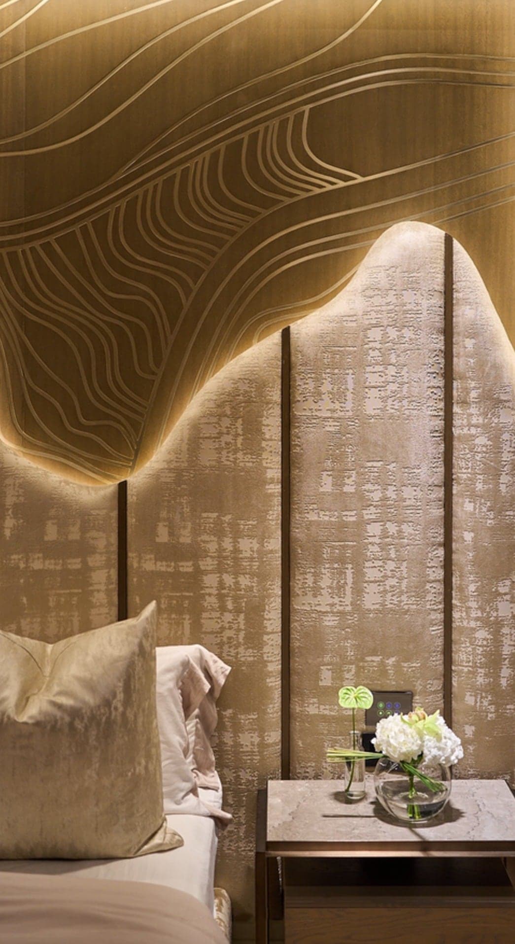 Master bedroom with a backlit contoured headboard wall in textured panels and integrated bedside joinery