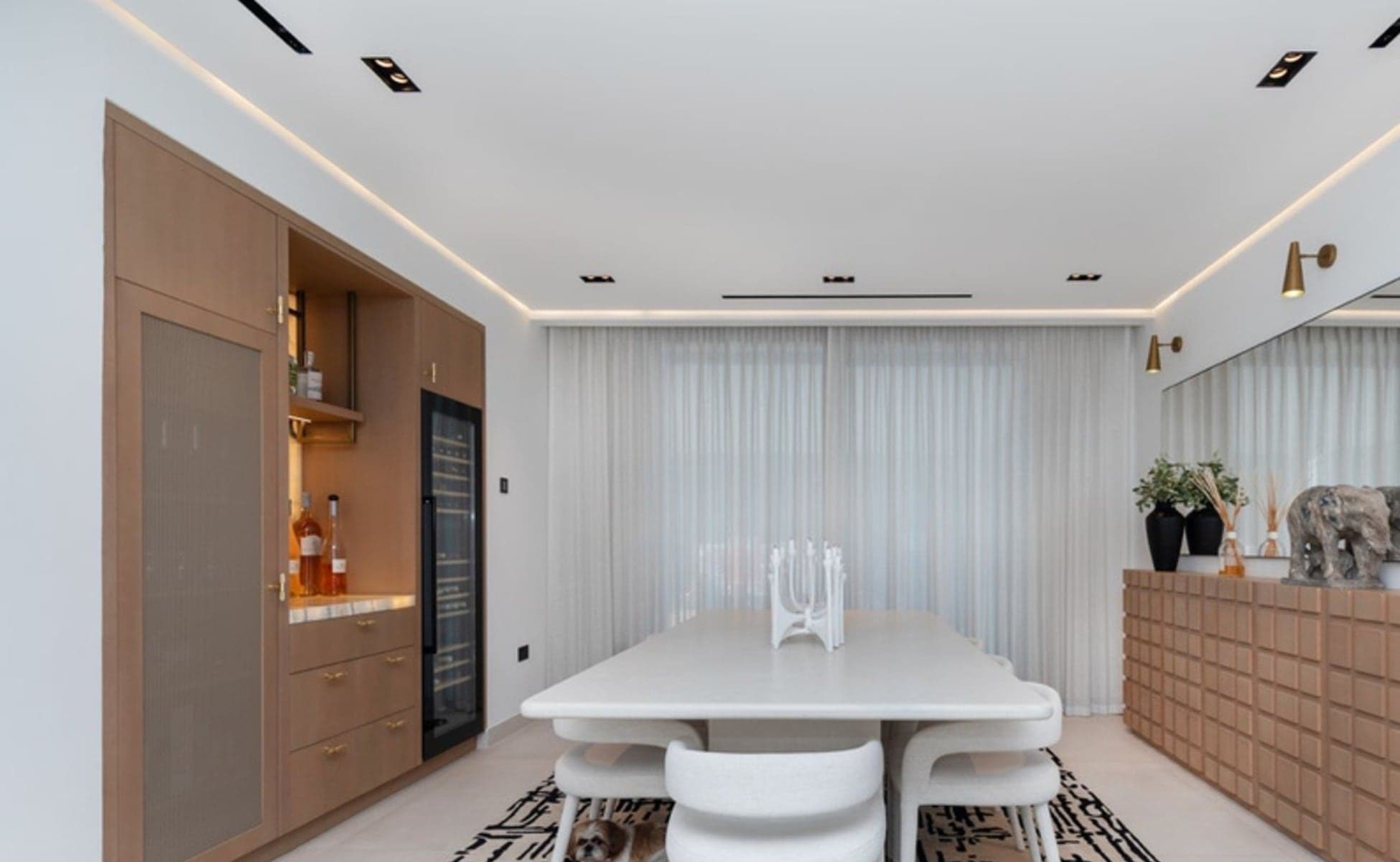 Dining room with full-height oak wall joinery, a sideboard and a round white table