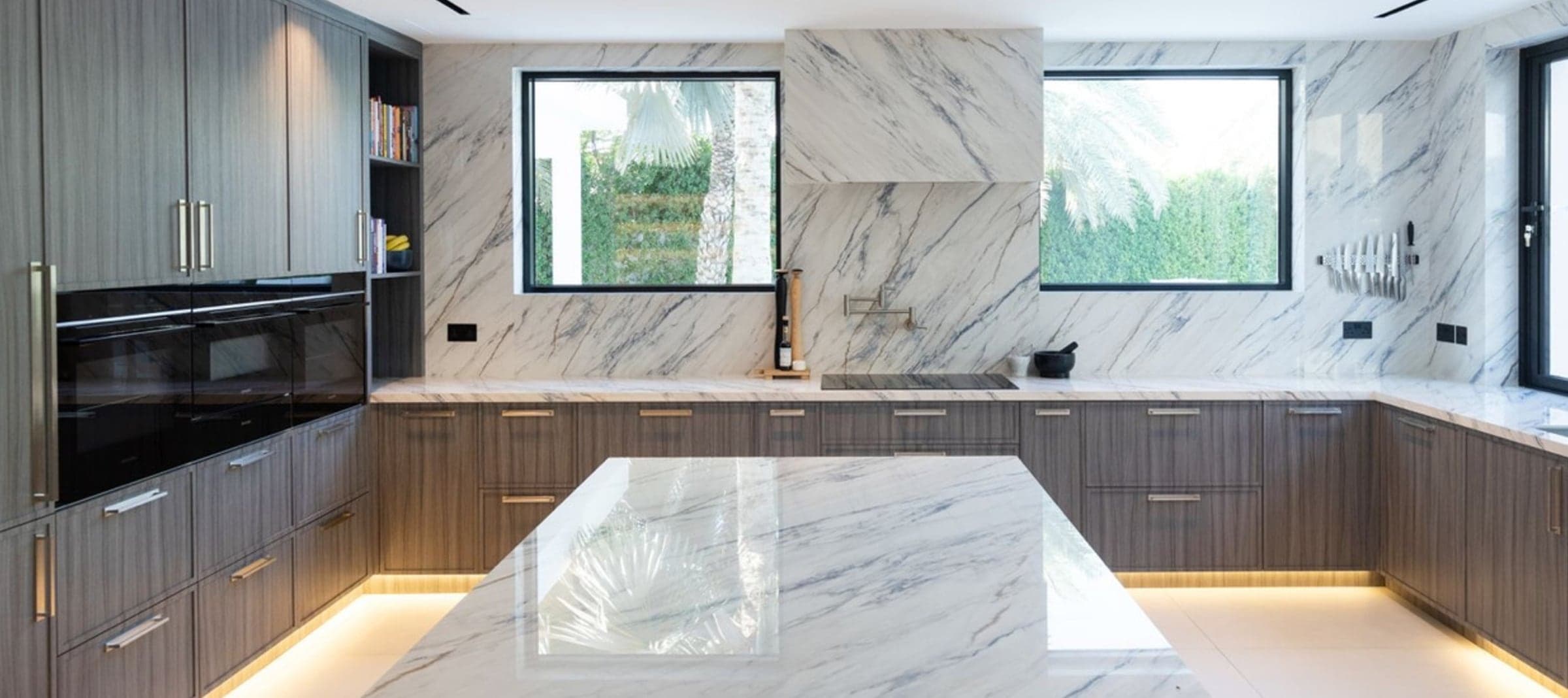 Kitchen with dark timber cabinetry, full-height white marble splashback and a marble island