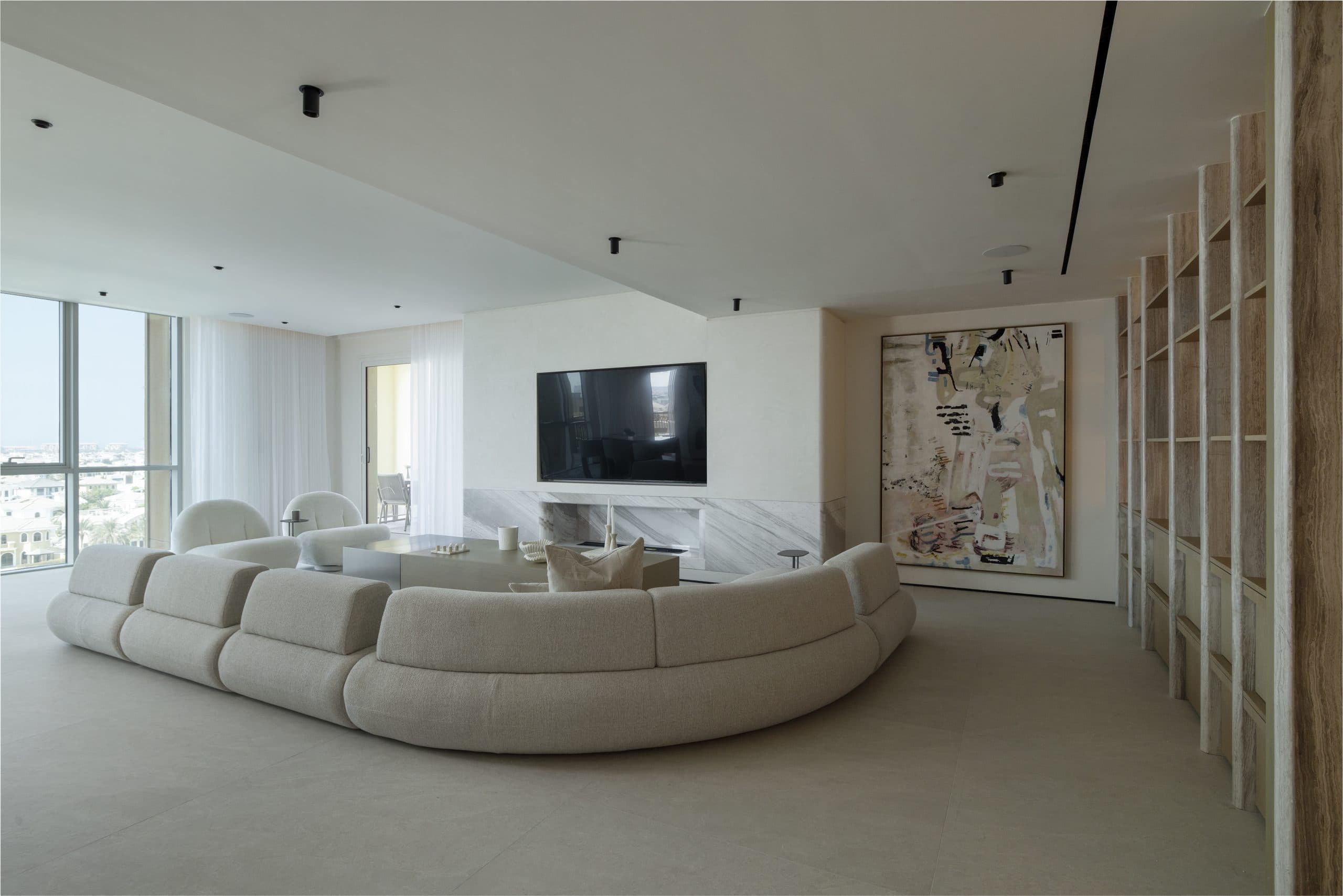 Open living room in a Dubai Marina apartment with oak shelving and a curved sofa