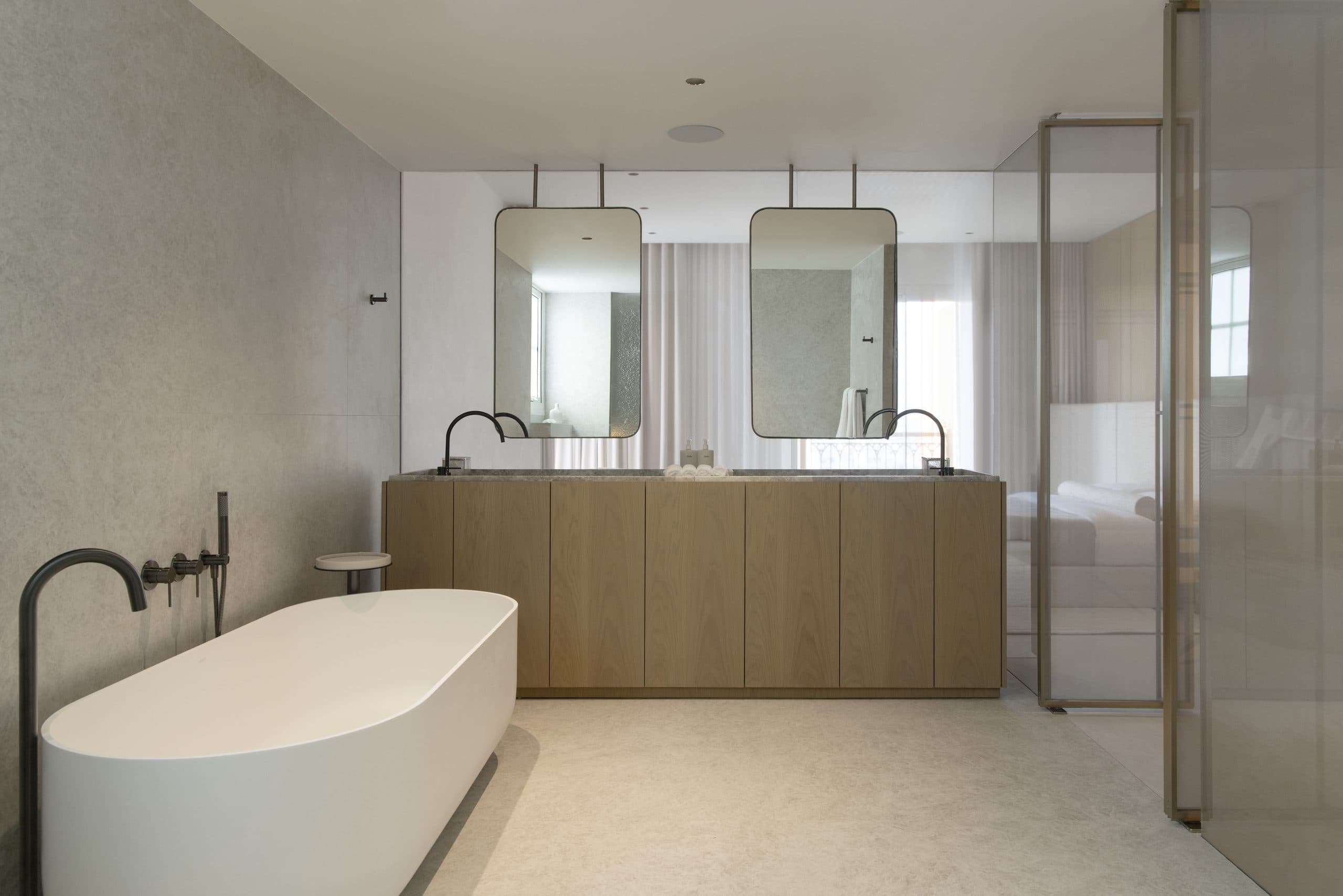 Master bathroom with an oak vanity, twin mirrors and a freestanding bath