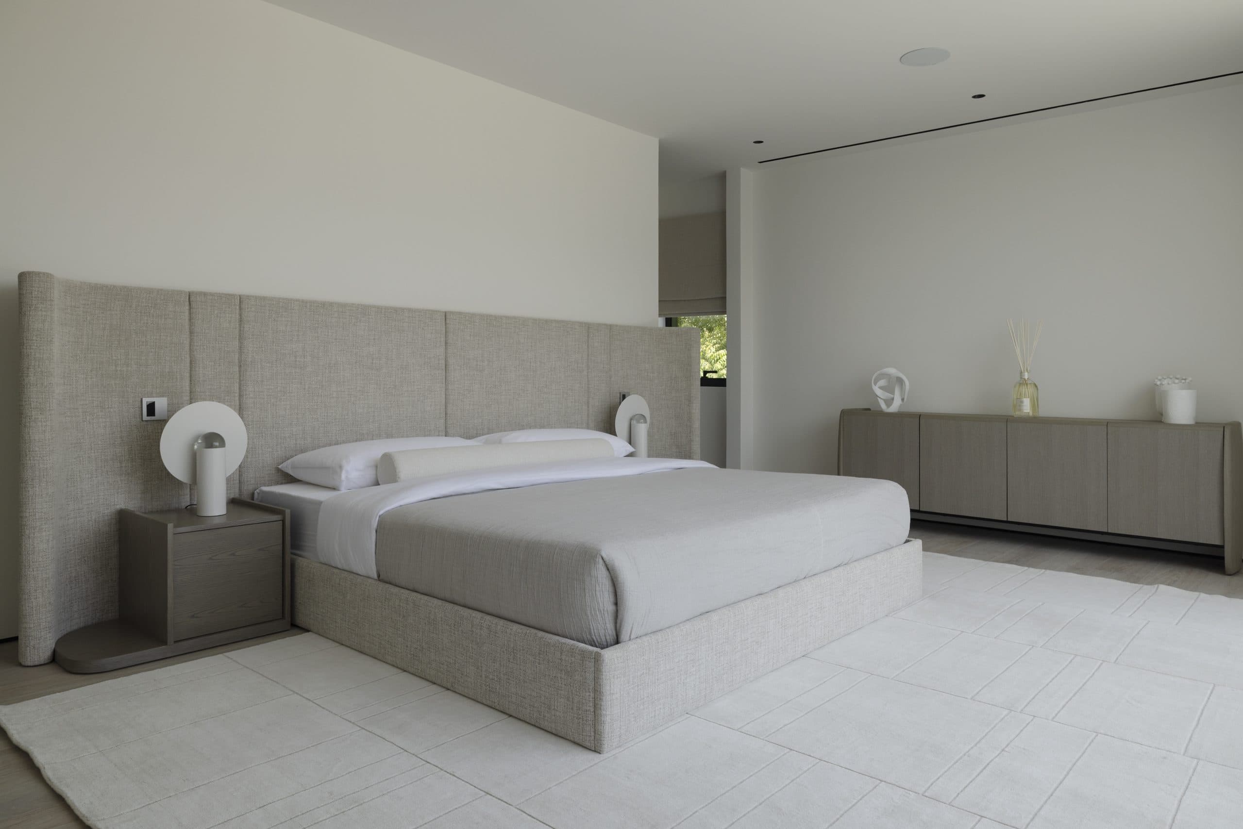 Master bedroom with a full-width upholstered headboard wall and a low sideboard