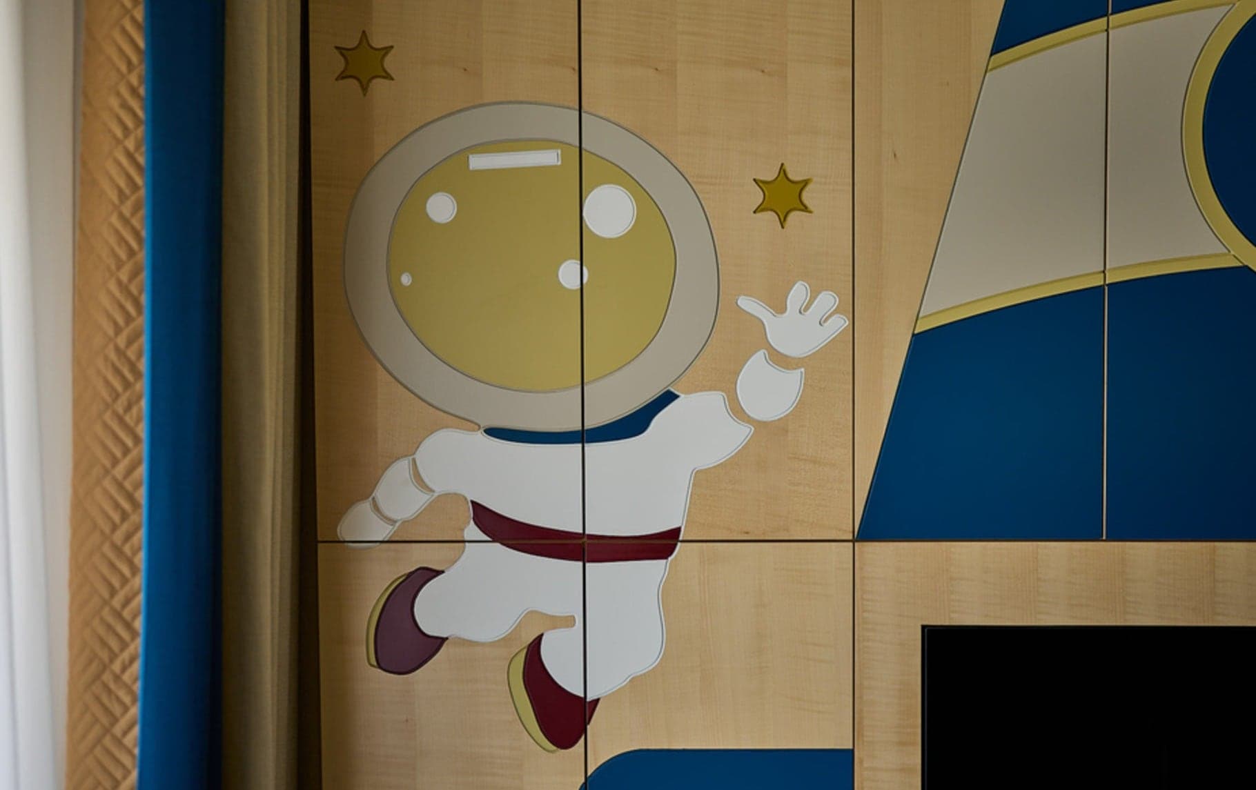Hand-painted astronaut panel detail on maple wardrobe doors