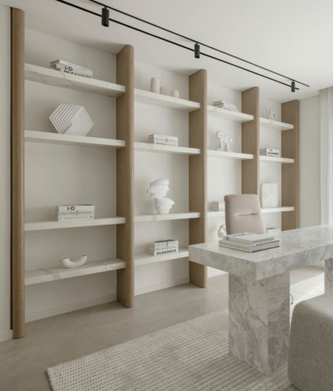 Open library shelving with a marble-based desk and track lighting