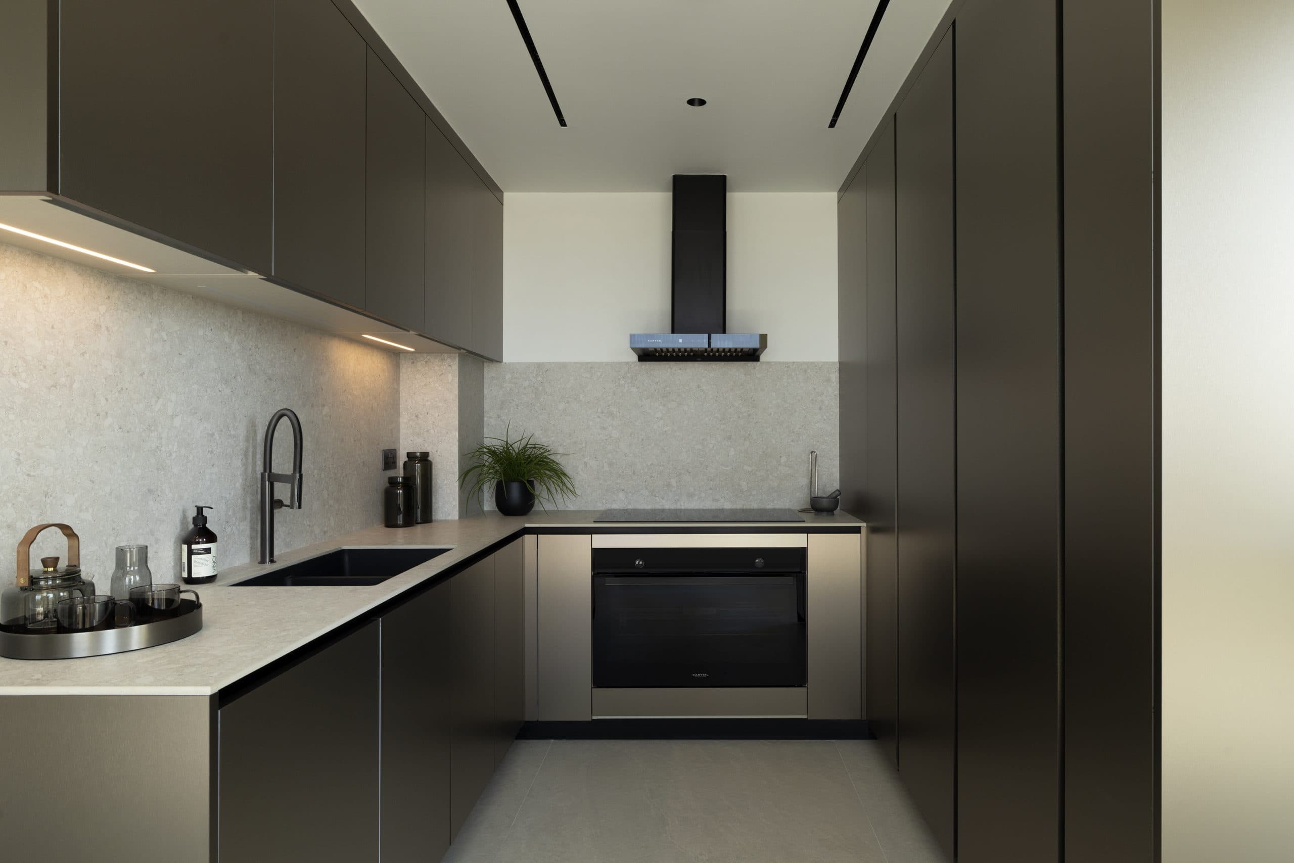 Back kitchen in dark handleless cabinetry with a stone splashback